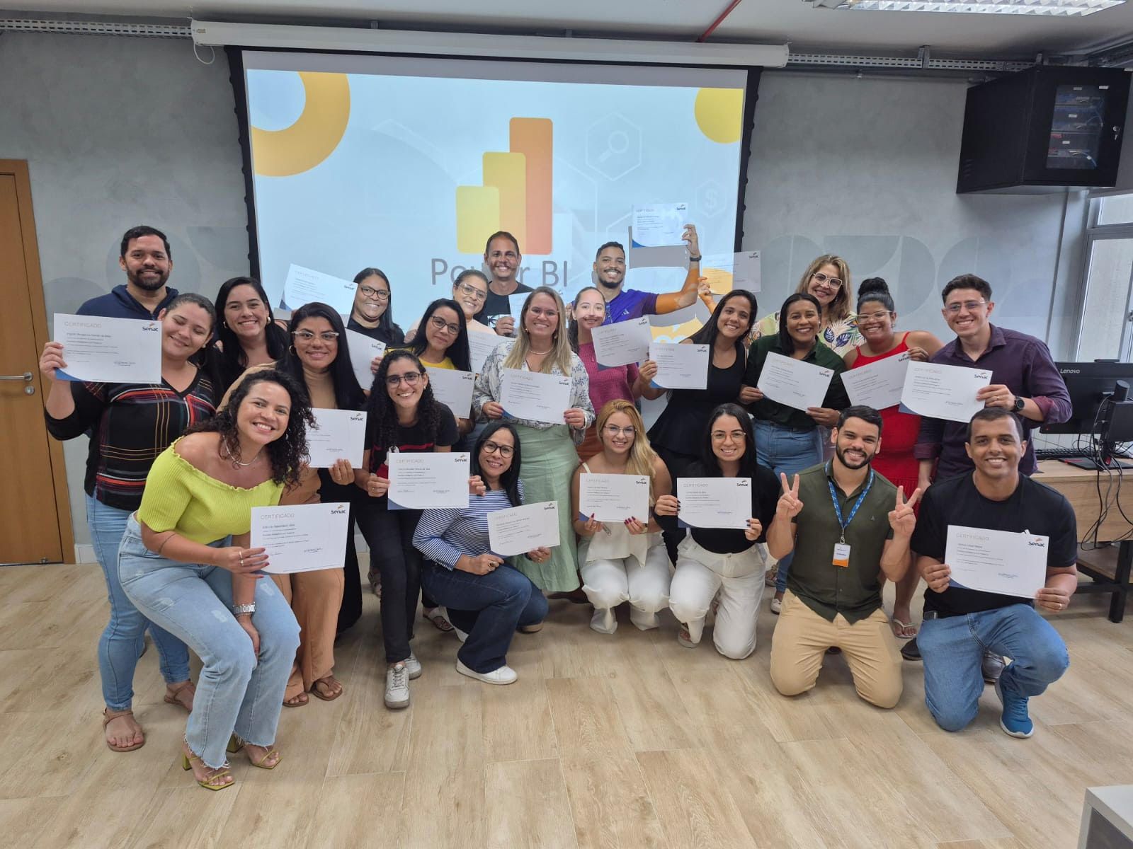 Turma de alunos formados segurando certificados em sala de aula